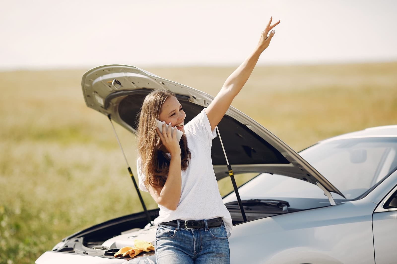A driver on the phone beside a car with its bonnet raised