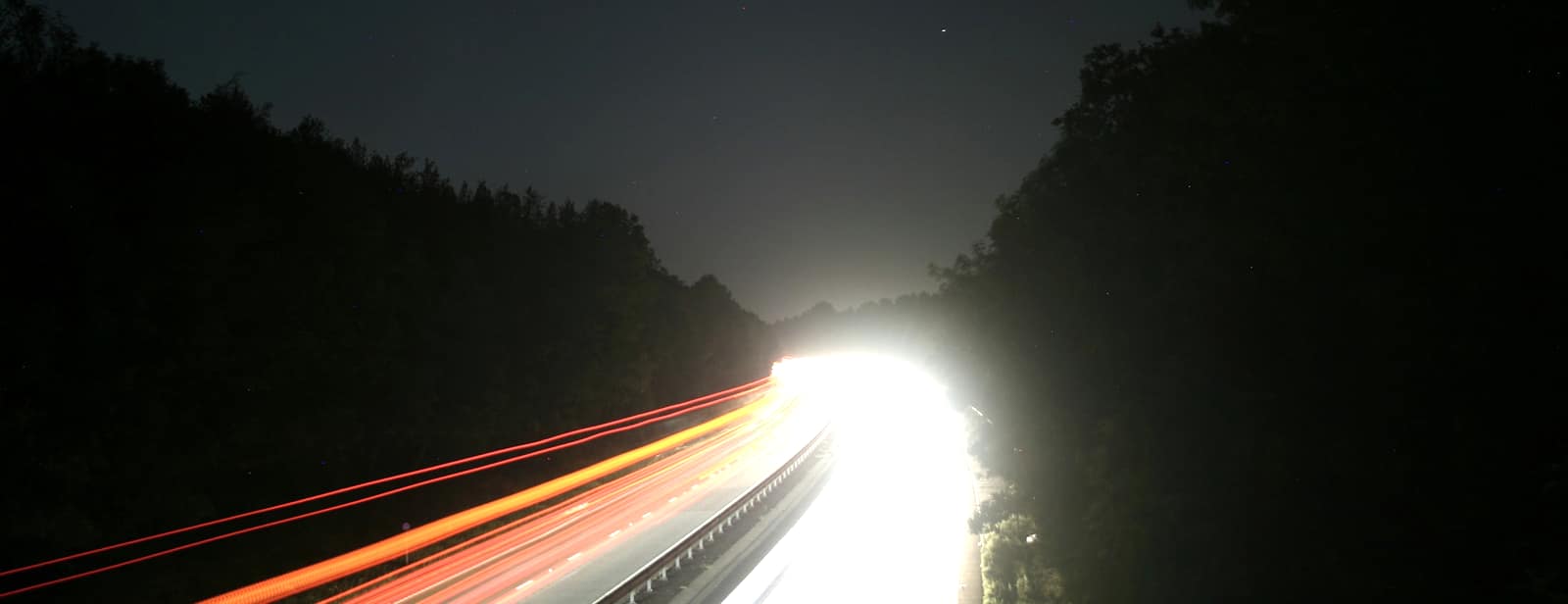 A dual carriageway at night lit by passing traffic